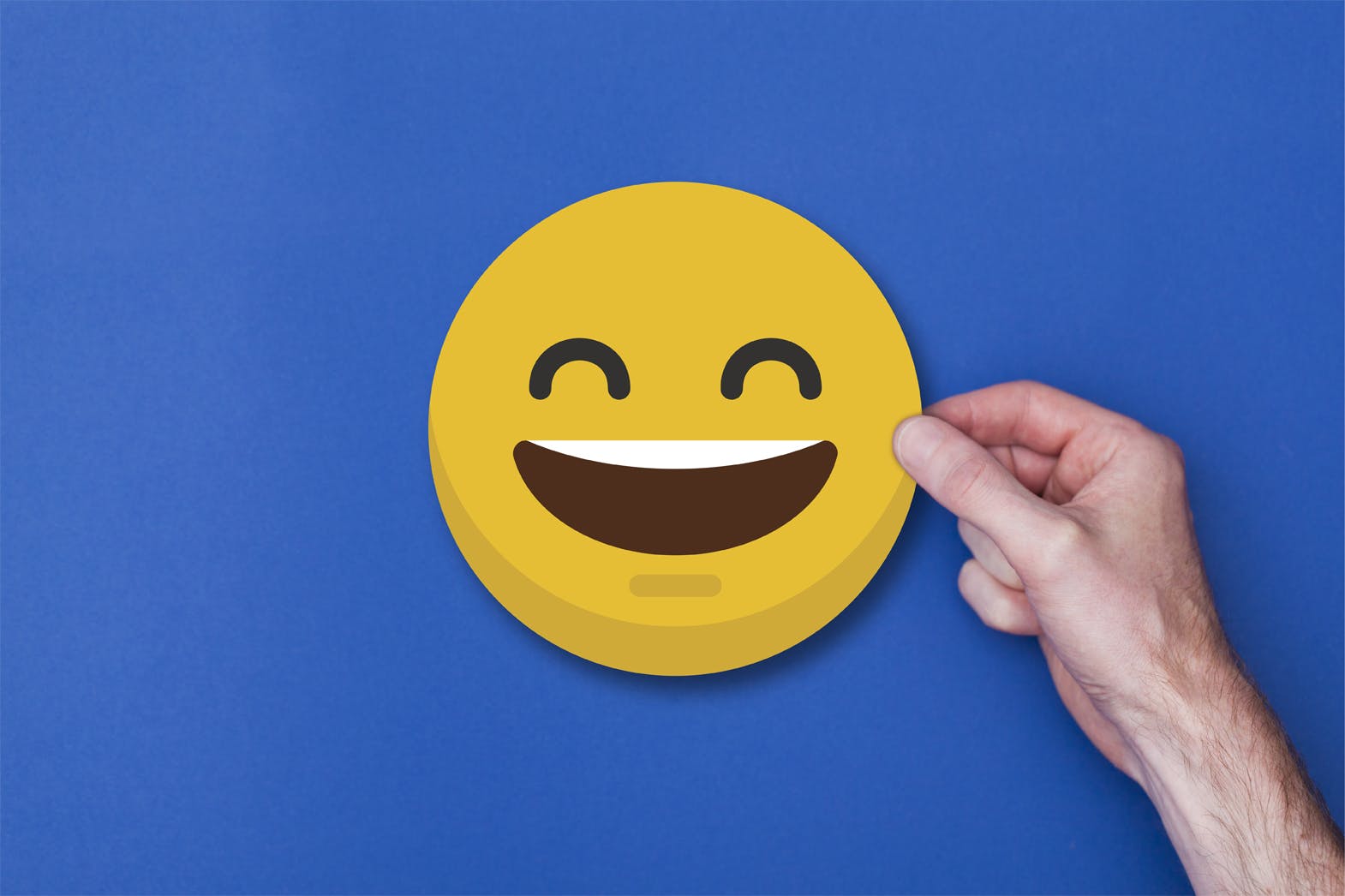 Male hand holding a emoji emoticon smiley head icon