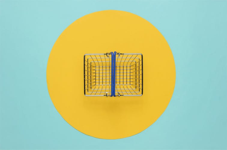 Mini shopping basket on blue background with yellow circle. Top view