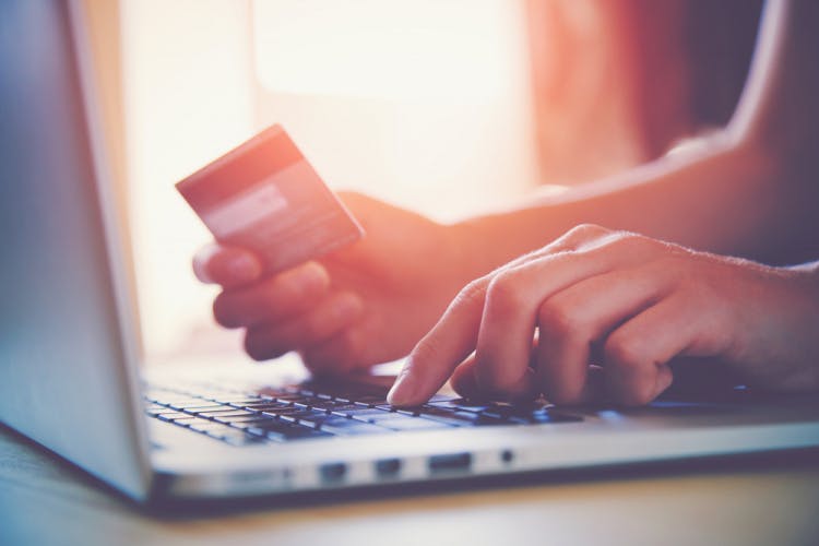 hands holding credit card at laptop